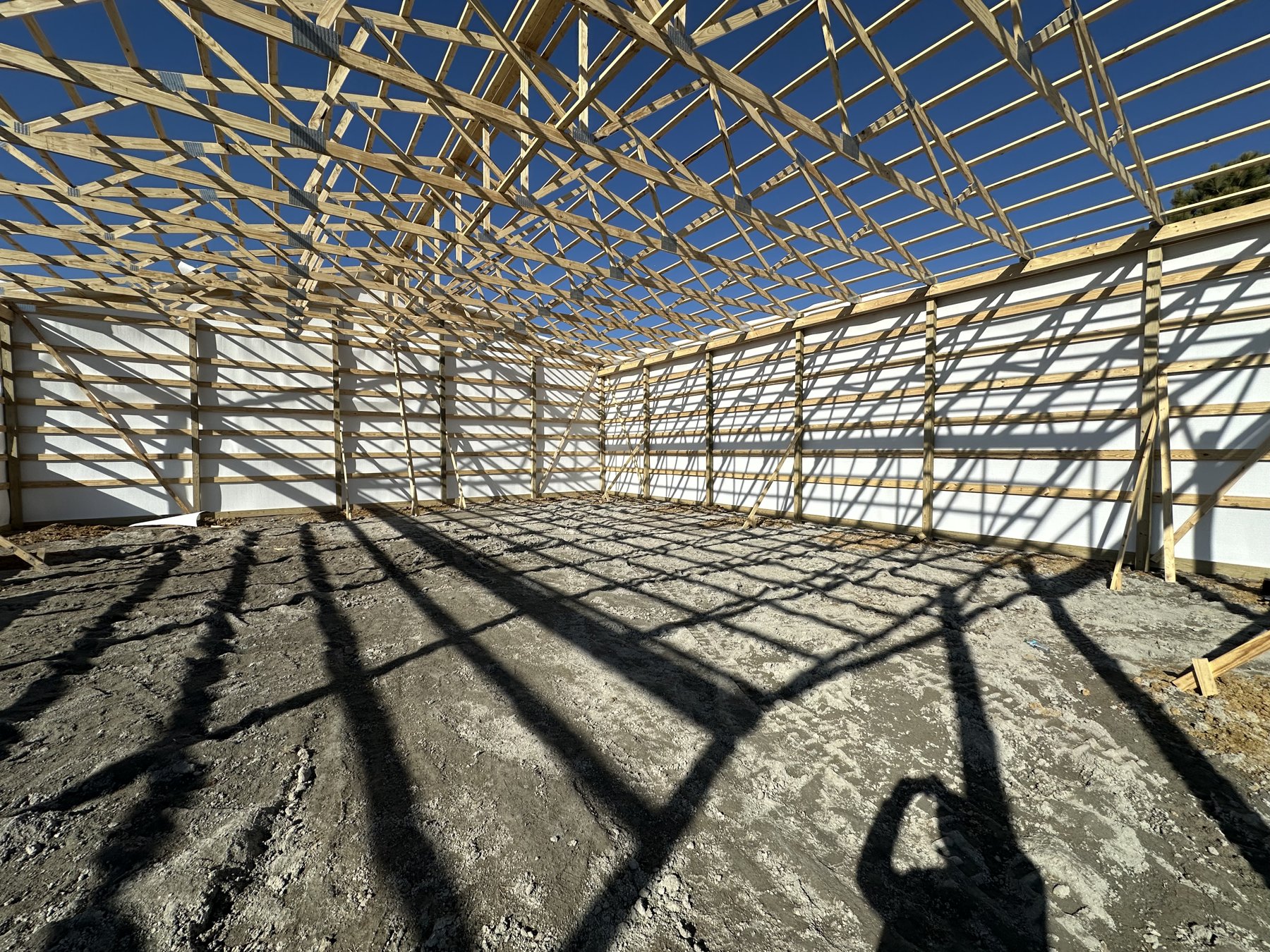 Timber posts, wall framing, and roof trusses during Meadows pole barn construction